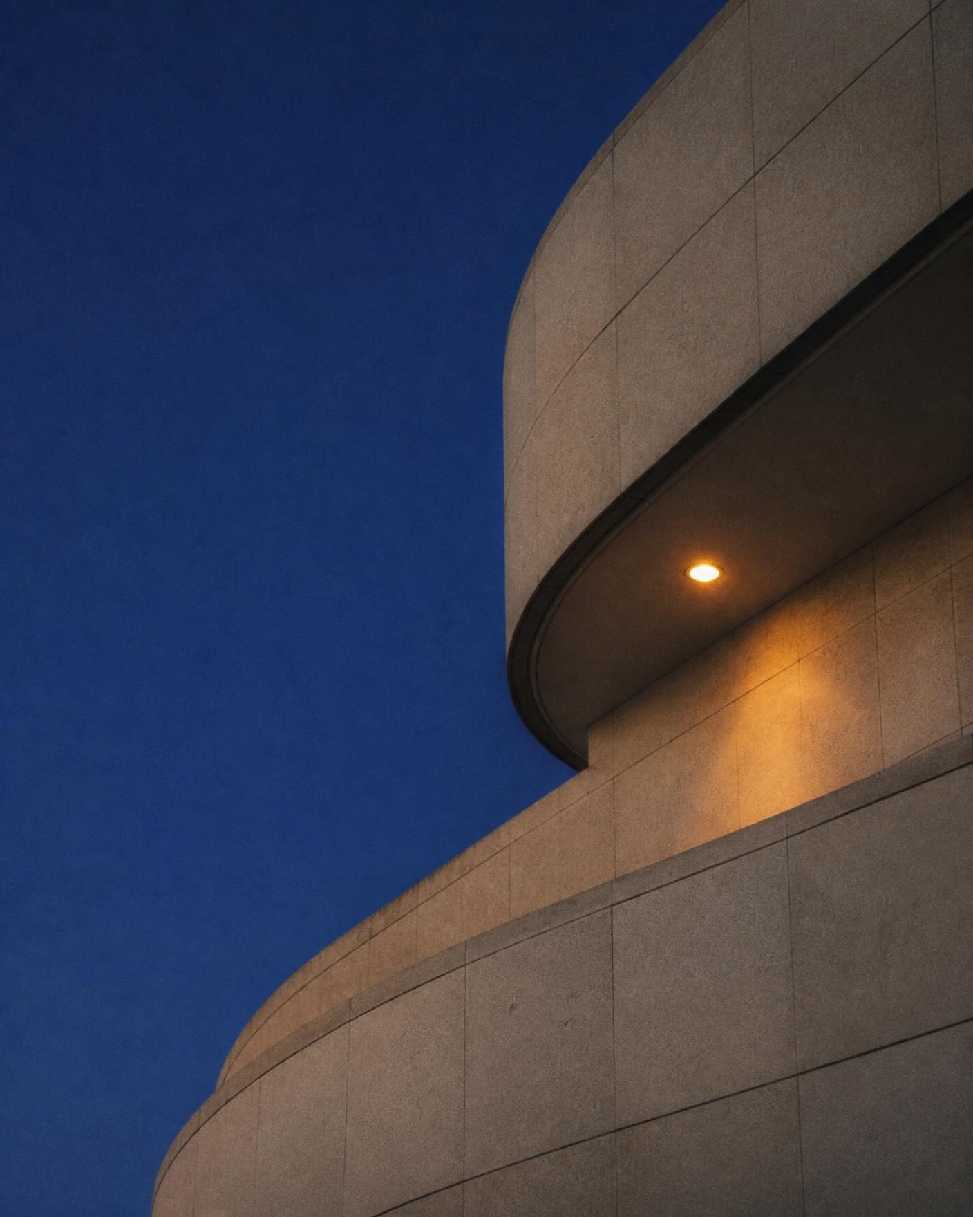 Curved stone facade against deep blue evening sky